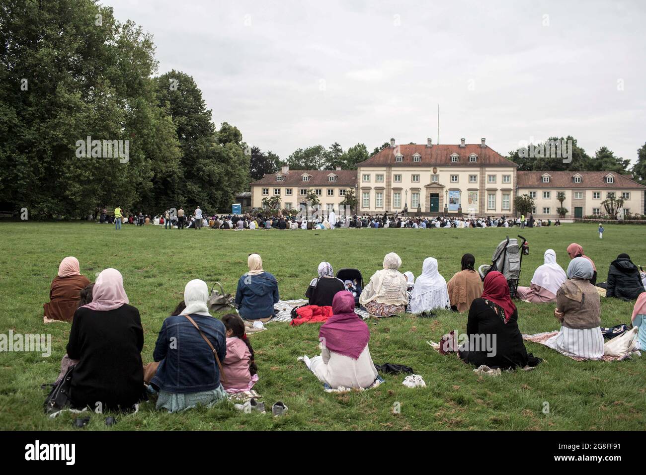 Hannover, Germania. 20 luglio 2021. I musulmani eseguono le preghiere di Eid al-Adha nel Georgengarten di fronte al Museo Wilhelm Busch. La Moschea di al-Huda ha organizzato per la prima volta la Festa della preghiera del sacrificio come evento all'aperto. La festa del sacrificio di Eid al-Adha è considerata la più importante celebrazione islamica ed è celebrata dai credenti di tutto il mondo. La festa commemora la volontà di Abramo di sacrificare uno dei suoi figli per dimostrare la sua fede a Dio. Credit: Eman Helal/dpa/Alamy Live News Foto Stock