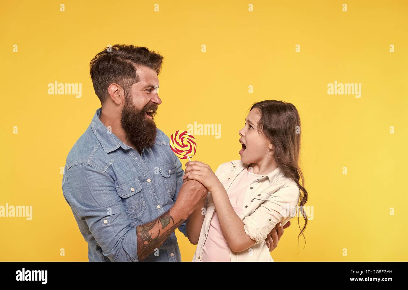 Uno per me nessuno per te. Padre prendere lollipop da infelice bambino. Lotta per il rollipop swirl sul bastone. Cibo dolce. Spuntino al dessert. Negozio di caramelle Foto Stock