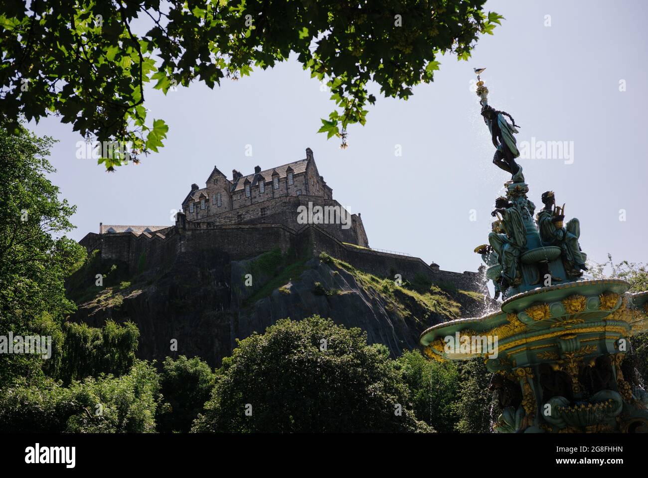 Guardando fino al Castello di Edimburgo dai Giardini di Princes Street tra gli alberi accanto alla Fontana di Ross. Foto Stock