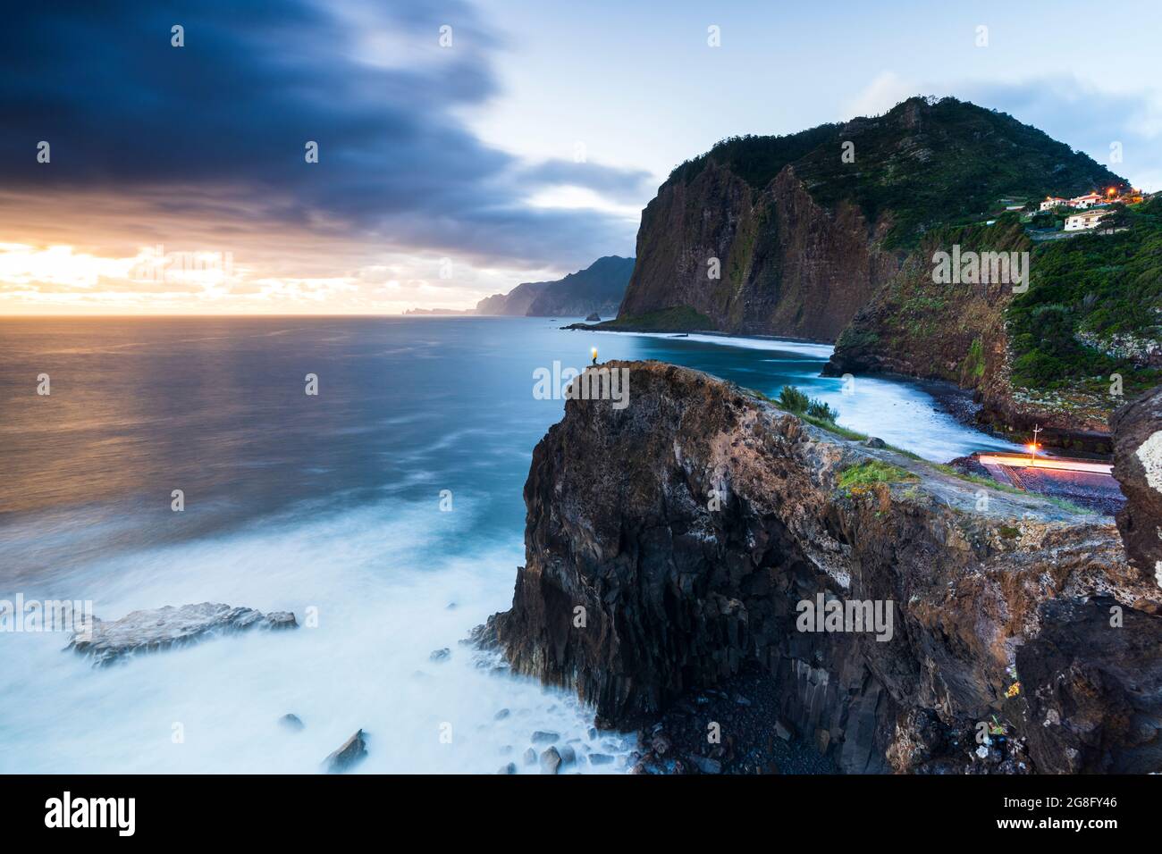 Escursionista con torcia da testa che ammira l'ora blu dalle scogliere al punto panoramico Miradouro do Guindaste, isola di Madeira, Portogallo, Atlantico, Europa Foto Stock