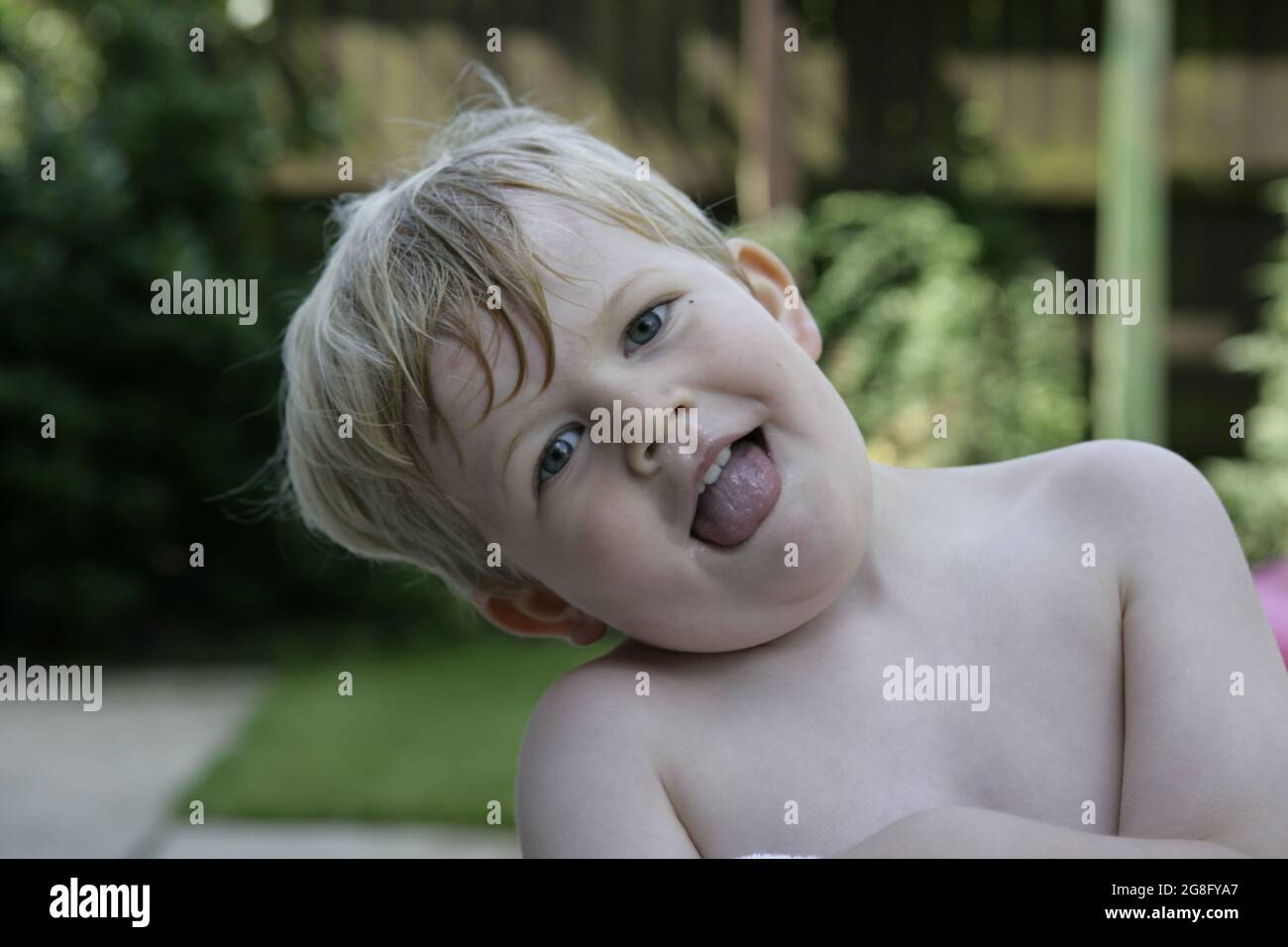 Giardino estivo esterno ritratto di bambino piccolo con i capelli biondi avvolti in asciugamano Foto Stock