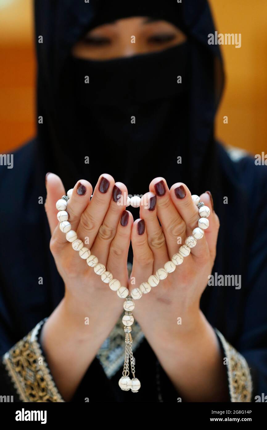 Primo piano delle mani di una donna musulmana in abaya mentre teneva il rosario e pregava, Emirati Arabi Uniti, Medio Oriente Foto Stock