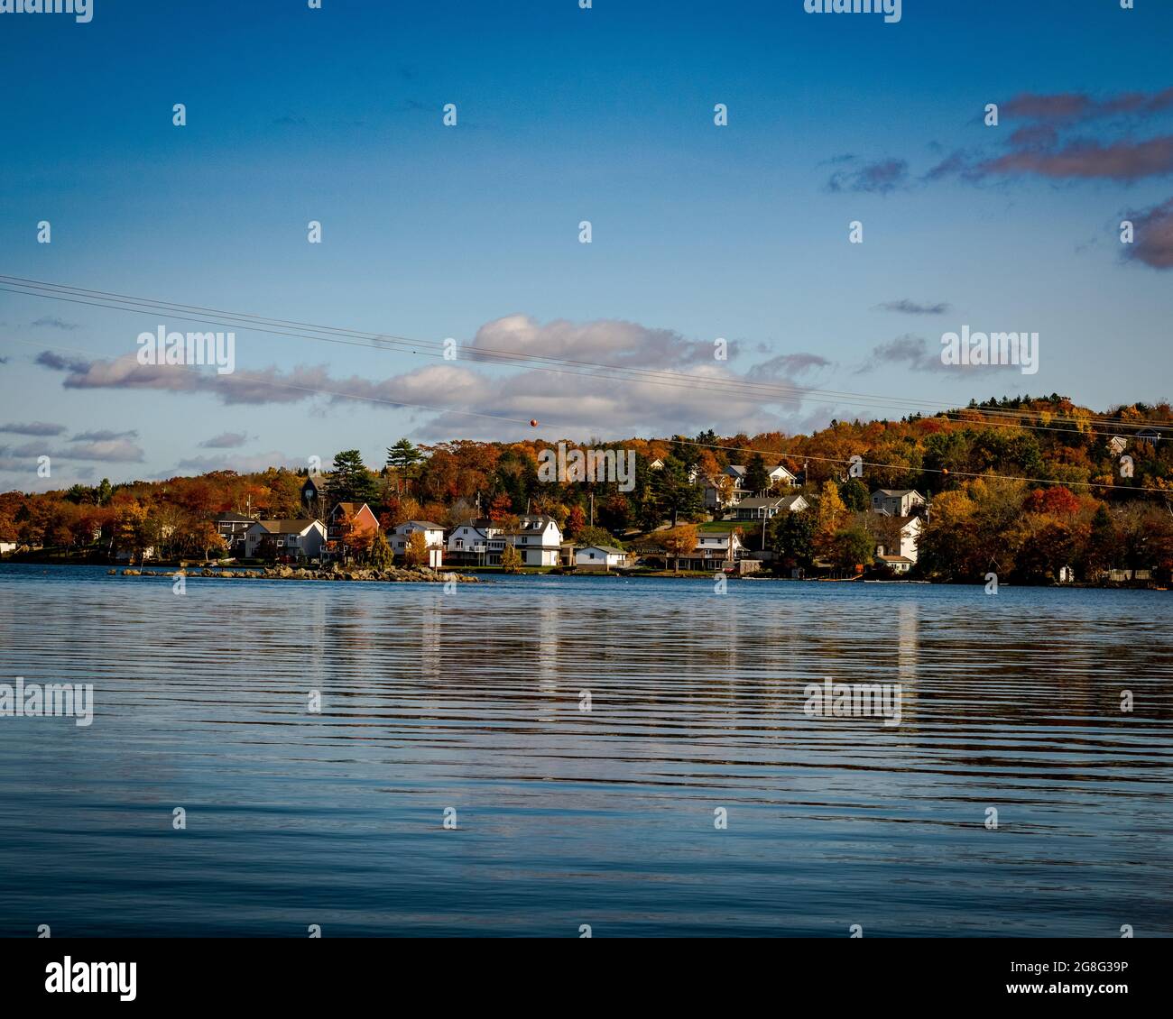 nuvole che galleggiano su una comunità sulle rive di un lago Foto Stock