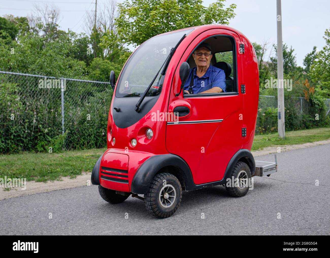 Uomo anziano che guida uno scooter completamente chiuso tutto il tempo utilità su un percorso a Ottawa, Canada Foto Stock