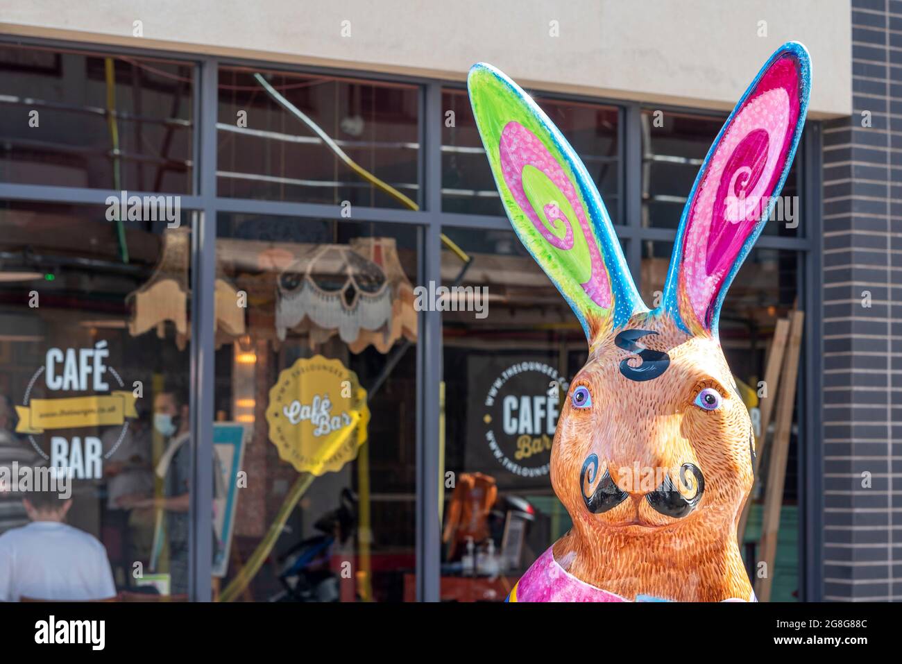 La testa dipinta di uno dei Hares About Town scultura percorso arte si affaccia in giornata di sole a Southend su Sea High Street, fuori da un bar caffetteria. Baffi francesi Foto Stock