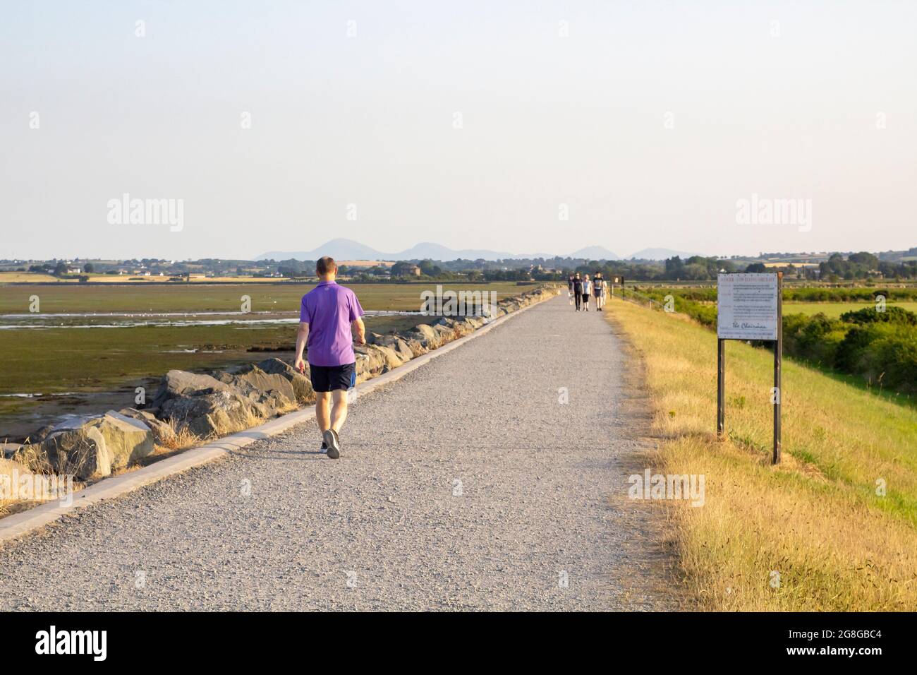 19 luglio 2021 UN uomo che cammina lungo le porte alluvionali a piedi sulla costa di Strangford Lough, proprio alla periferia della contea di Newtownards, in Irlanda del Nord a t Foto Stock
