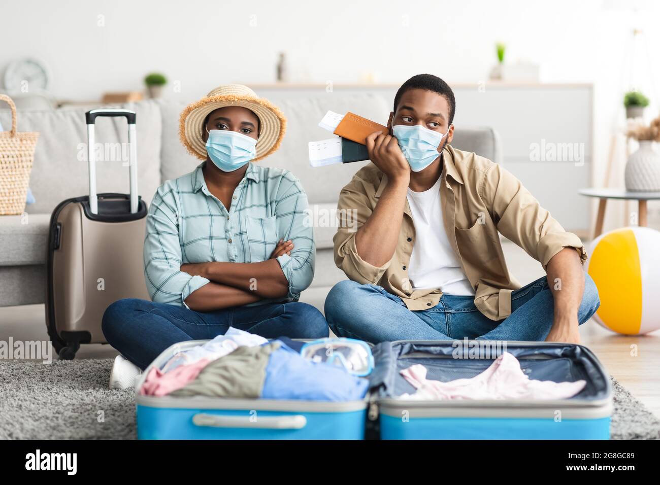 Una coppia di turisti afro-americani frustrati che tiene i biglietti d'aereo a casa Foto Stock