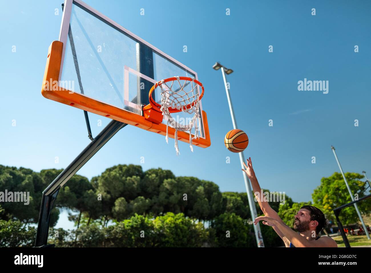 Mano di sportivo che gioca a basket gettando la palla nel parco giochi, facendo colpo di colpo di salto Hook, vista da dietro. Scatto di precisione Foto Stock