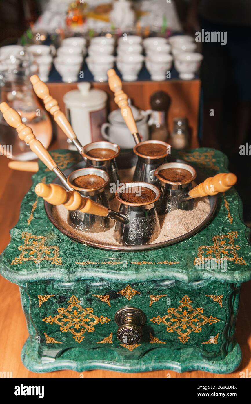 Caffè turco estratto sulla sabbia in cezve. Caffè orientale, orientale. Foto Stock