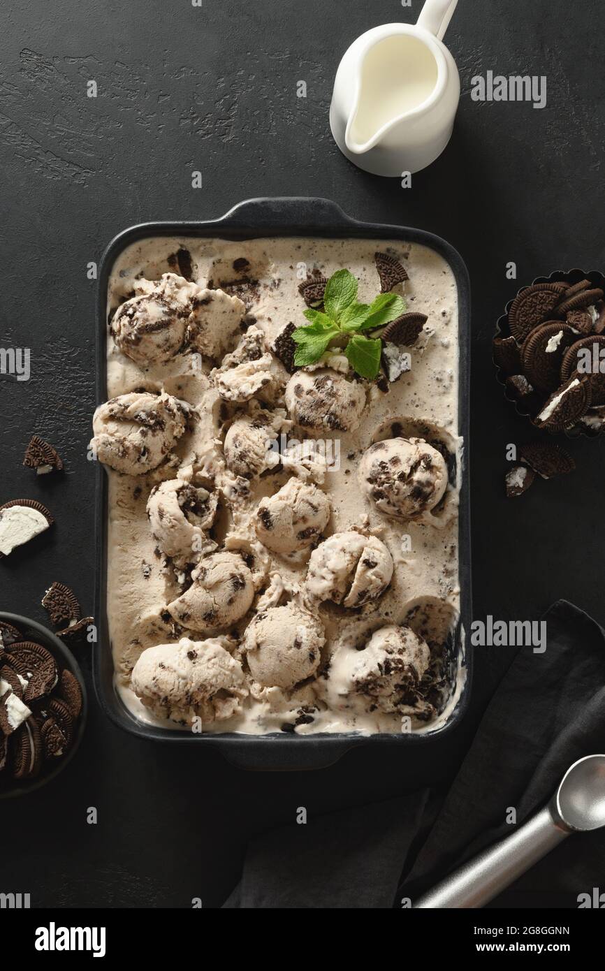 Gelato cremoso con biscotti al cioccolato in contenitore nero. Vista dall'alto. Formato verticale. Foto Stock