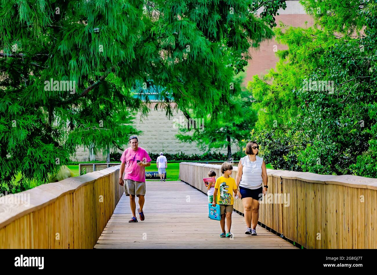 Una famiglia gioca a Pokemon Go mentre attraversa il ponte pedonale di Langan Park durante il Pokemon Go Fest 2021, 17 luglio 2021, a Mobile, Alabama. Foto Stock
