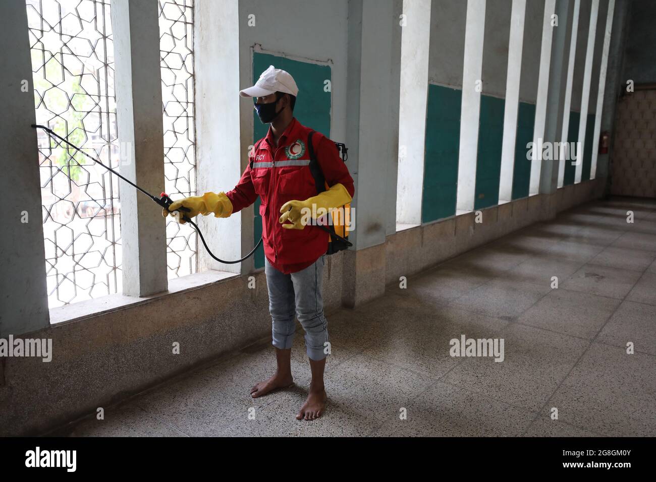 L'operatore sanitario disinfetta la moschea dopo aver completato la preghiera alla Moschea di Bait ul Mukarram di Dhaka durante l'epidemia di corona. Foto Stock