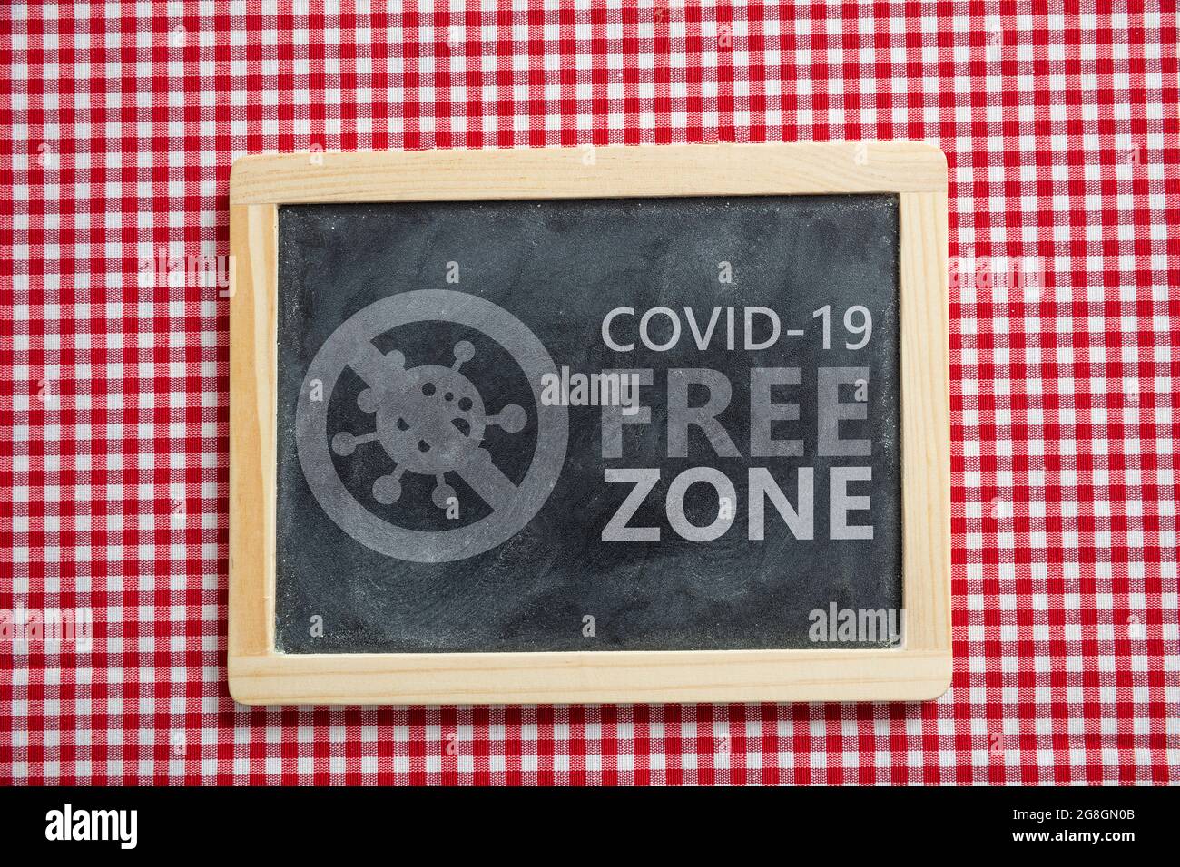 Cartello zona libera Covid. Etichetta di testo COVID 19 ZONA LIBERA su sfondo rosso a scacchi. Taverna, ristorante aree disinfettate, vaccinato solo concetto Foto Stock