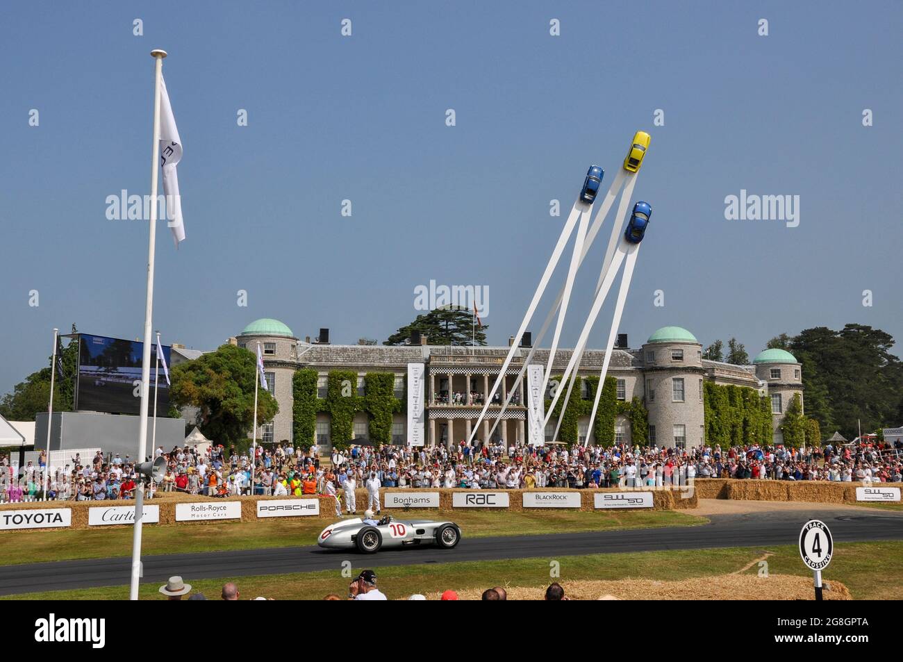 Stirling Moss guida Mercedes Benz W196 auto storica al Goodwood Festival of Speed evento, passando Goodwood House e la caratteristica centrale Porsche Foto Stock