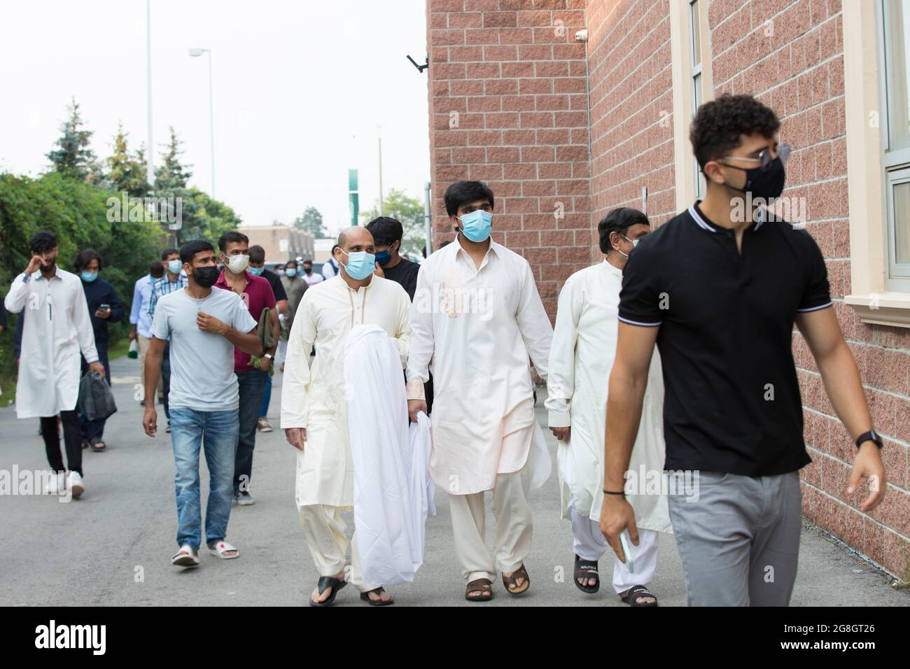 Un gruppo di uomini islamici sta camminando verso il retro della moschea per l'addio del primo ministro Justin Trudeau che dà il discorso all'interno della moschea durante Eid Foto Stock