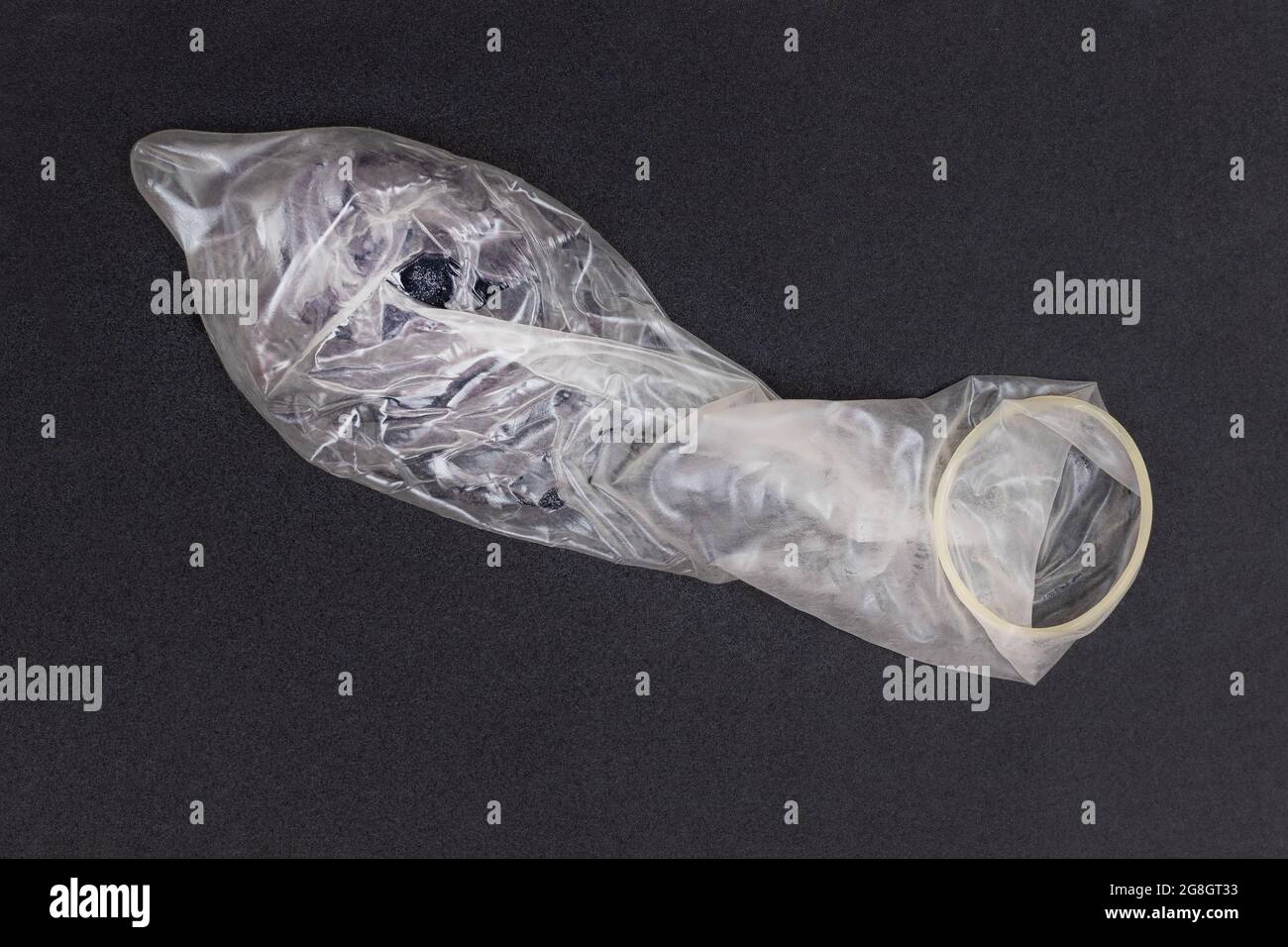 Usato Latex Condom su sfondo nero Foto Stock