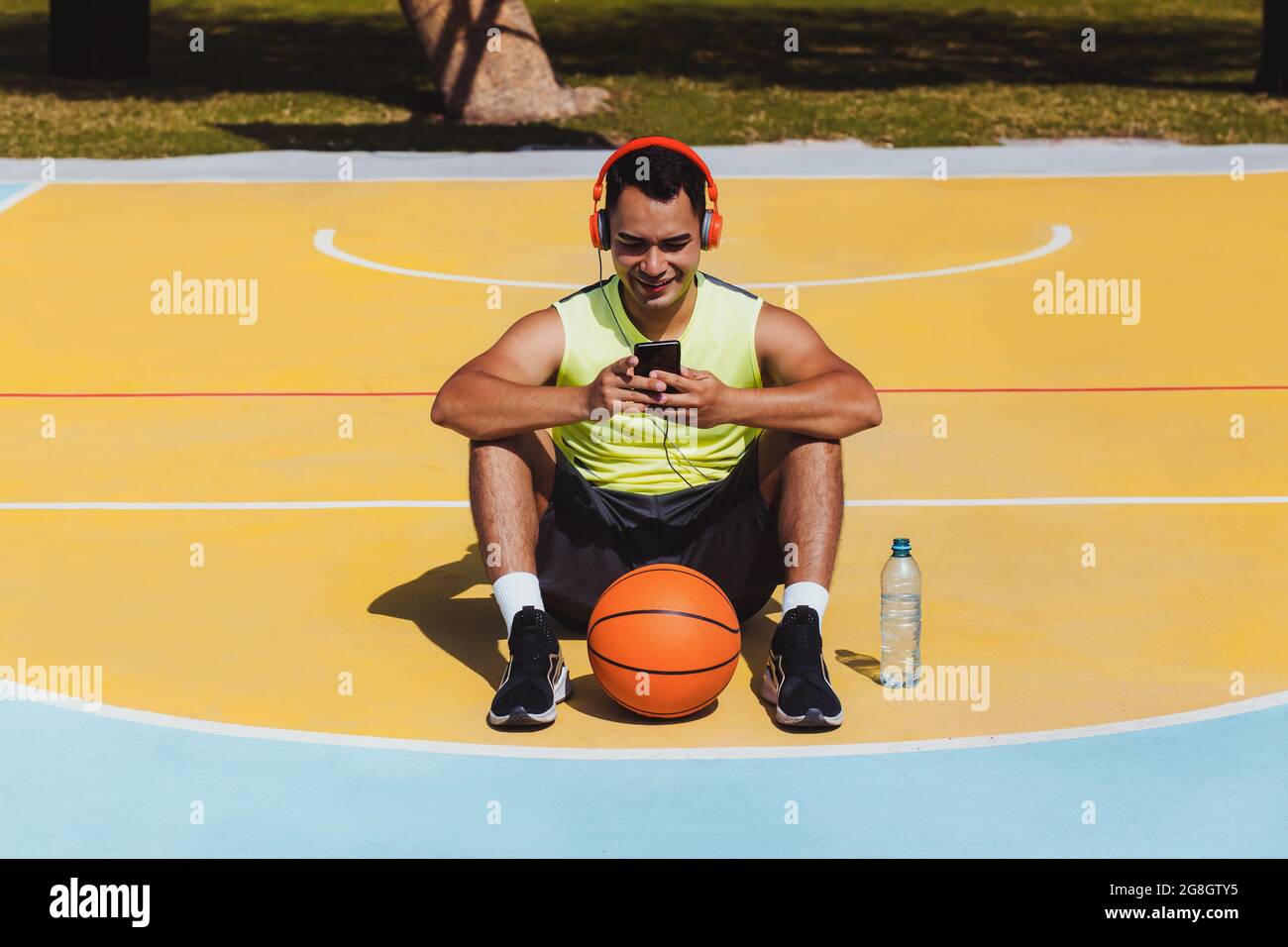 Ritratto di giovane latino che gioca a basket con cuffie e telefono in Messico e America Latina Foto Stock