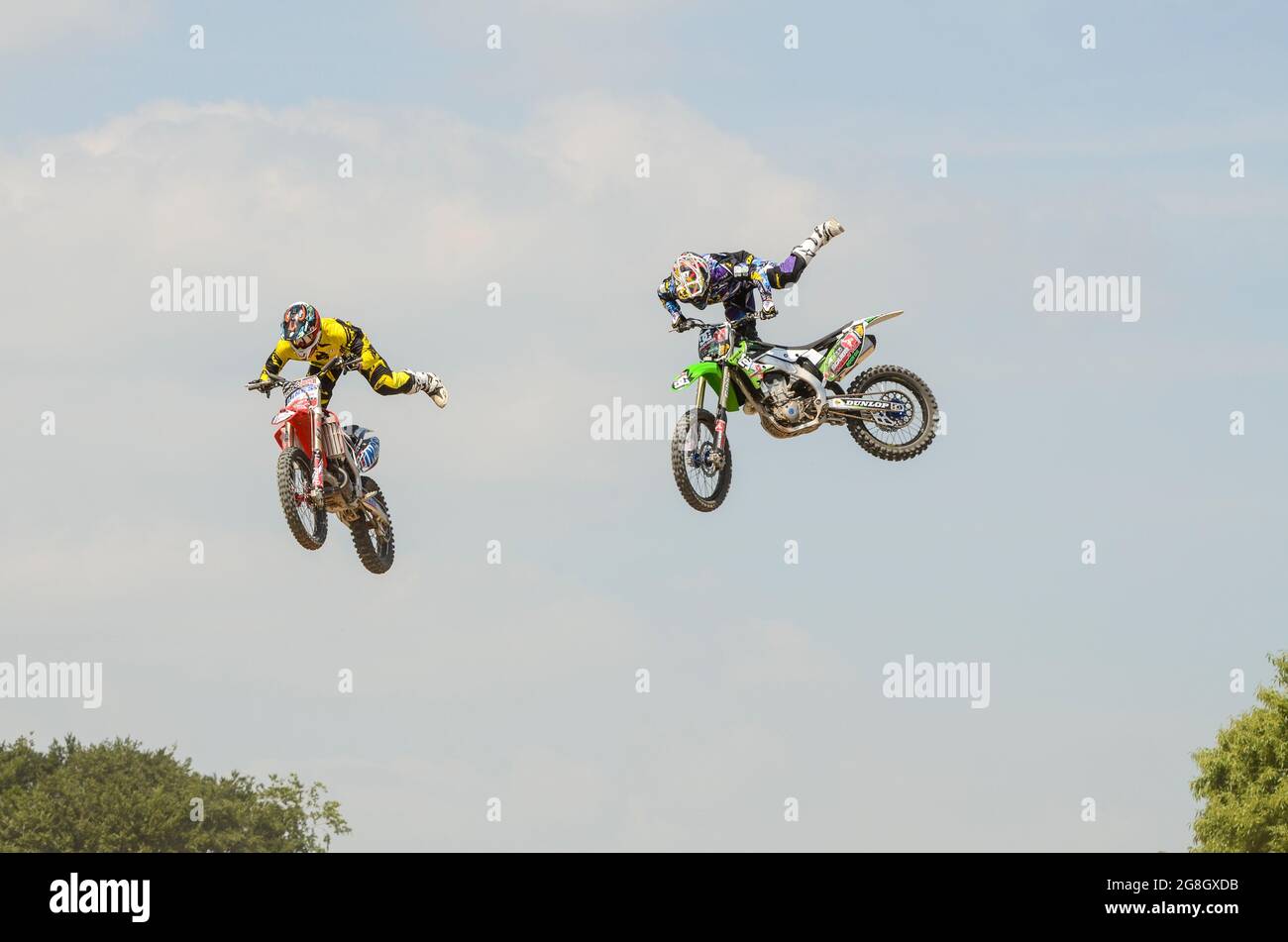 I piloti di MotoX stunt che volano in aria all'evento Goodwood Festival of Speed, Regno Unito. EVENTO GAS (Goodwood Action Sports). Coppia di acrobazie motociclistiche Foto Stock
