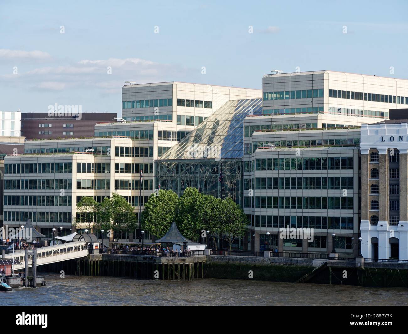 Londra, Greater London, England, giugno 12 2021: Vista verso un molo o molo e un edificio di vetro sulla riva sud del fiume tamigi Foto Stock