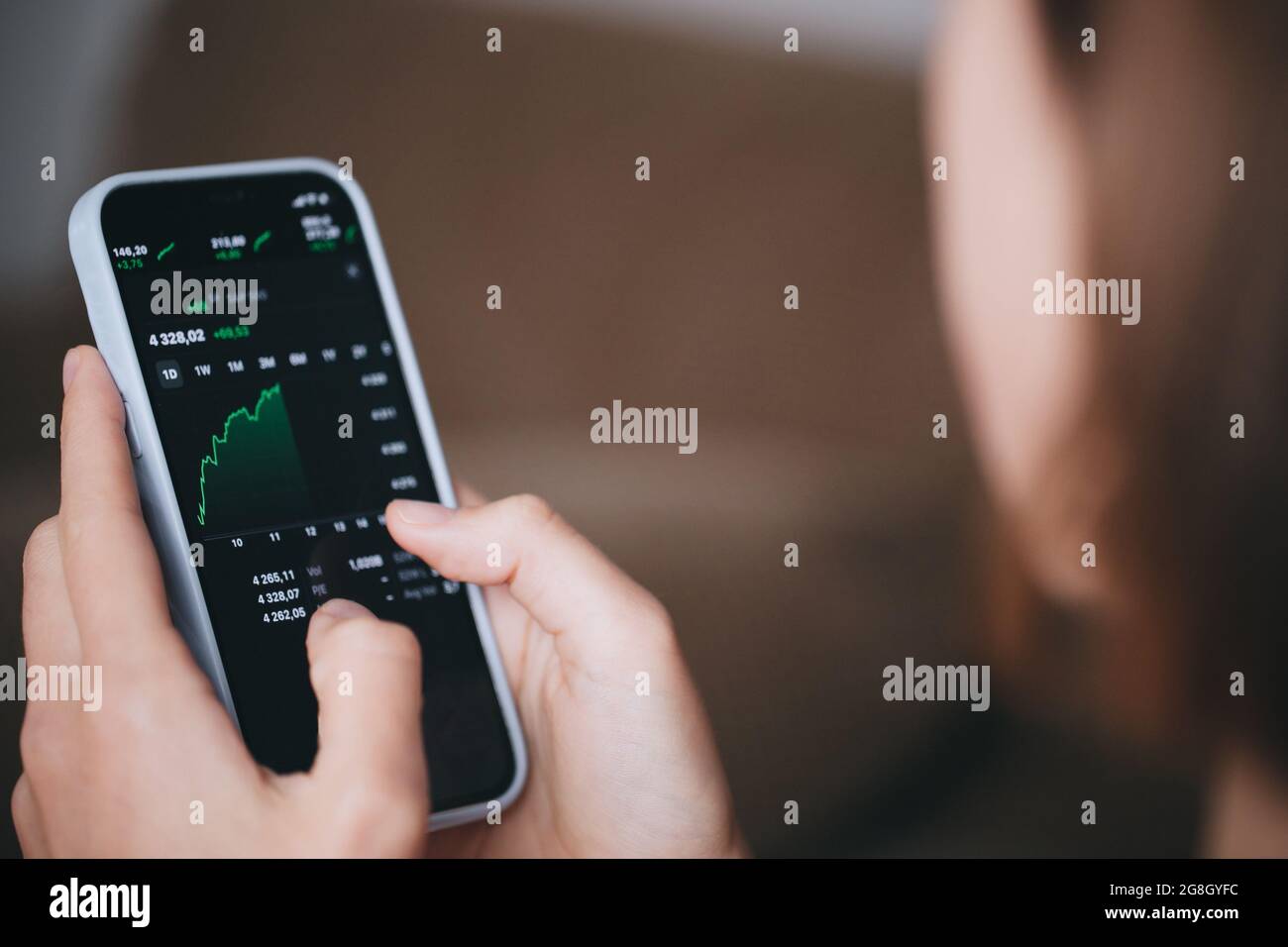 Investitore di borsa giovane donna in possesso di un telefono di investimento app indice di crescita grafico Foto Stock