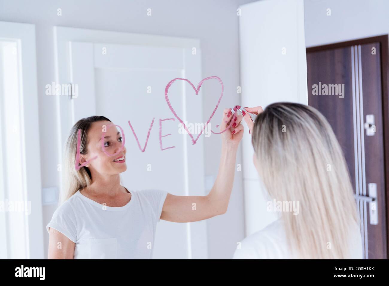 Donna disegnando il cuore sullo specchio da rossetto. Concetto di giorno di San Valentino. Foto Stock