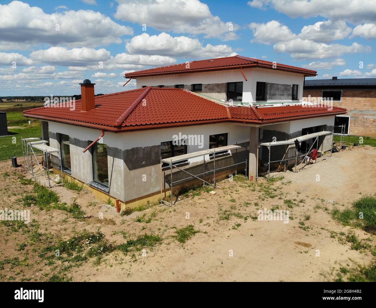 Casa in costruzione con piastrelle di colore marrone rosso e pittura in corso durante la soleggiata giornata estiva Foto Stock