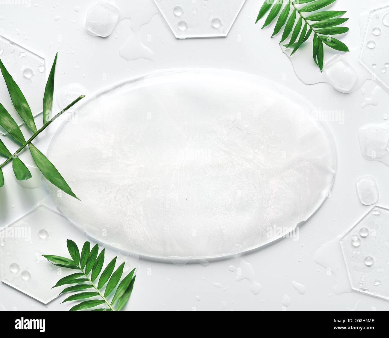 Sfondo ghiacciato con piatto ovale e cubetti di ghiaccio. Sfondo bianco con foglie esotiche di palma. Minima disposizione piatta, vista dall'alto con spazio per la copia, posizione Foto Stock