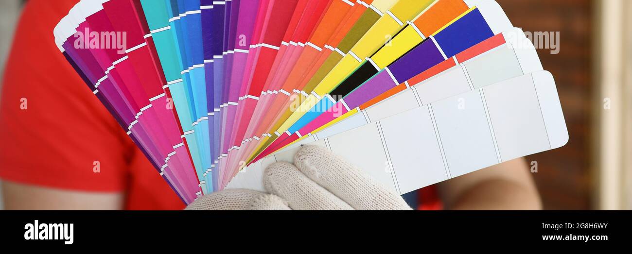 Un uomo in guanti mostra i campioni di colore in un profilo storato. Una tavolozza di colori per creare un design in un appartamento Foto Stock