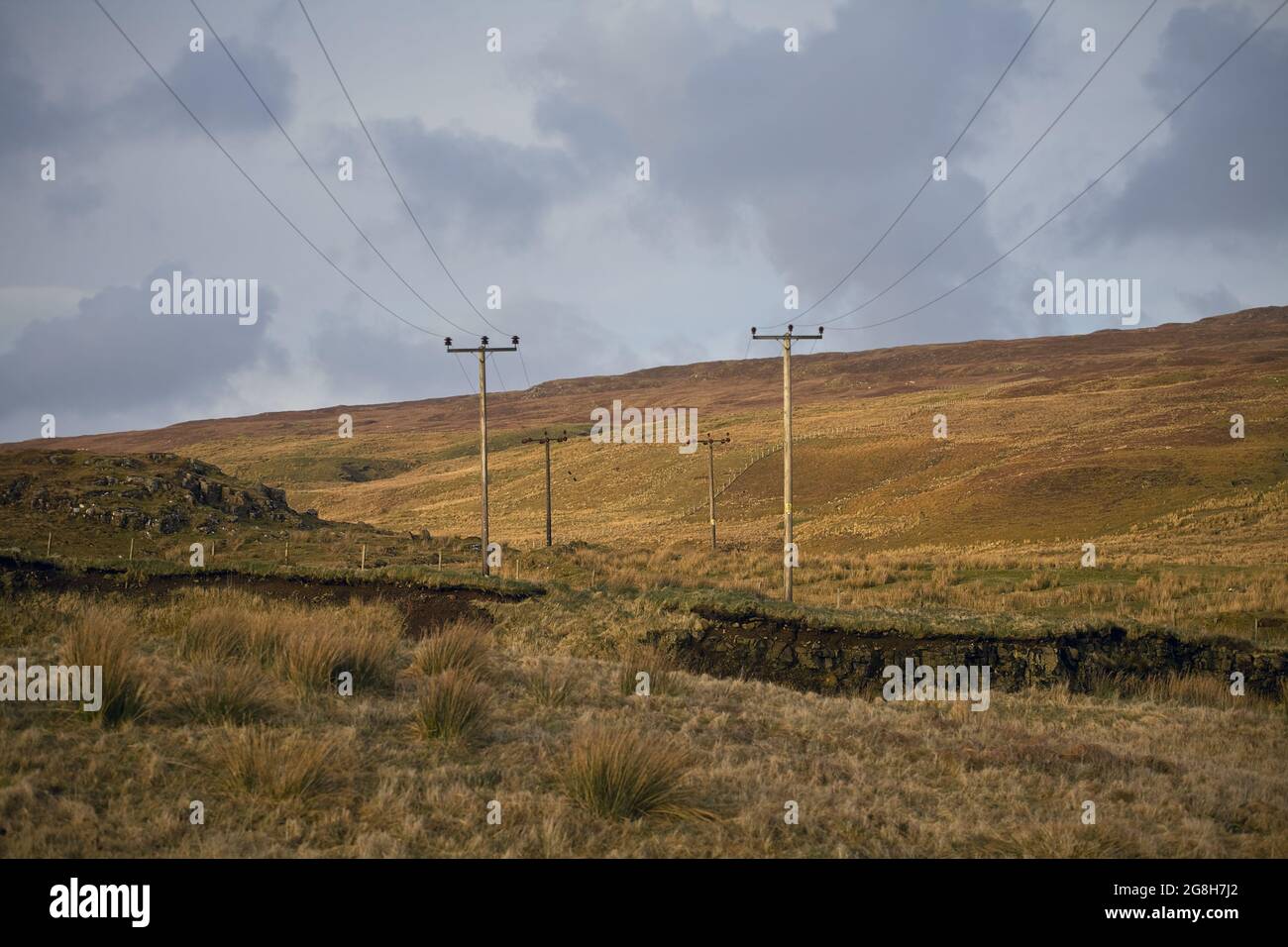 Pali elettrici nella Scozia rurale sui campi d'oro dell'Isola di Skye - Regno unito. Foto Stock