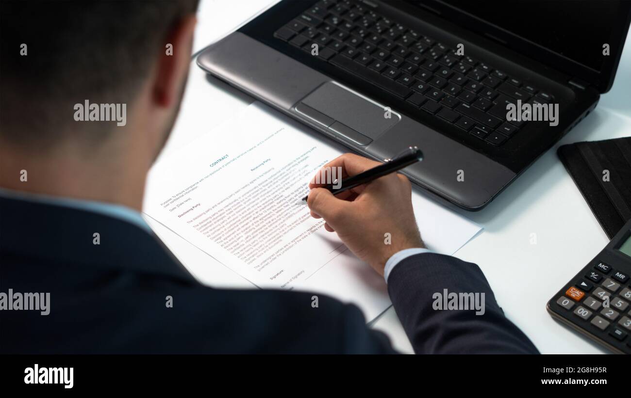 Uomo d'affari guarda sopra i termini e le condizioni sul contratto prima di mettere il segno su una carta. Uomo che firma un accordo legale, contratto. Vista posteriore. Foto Stock