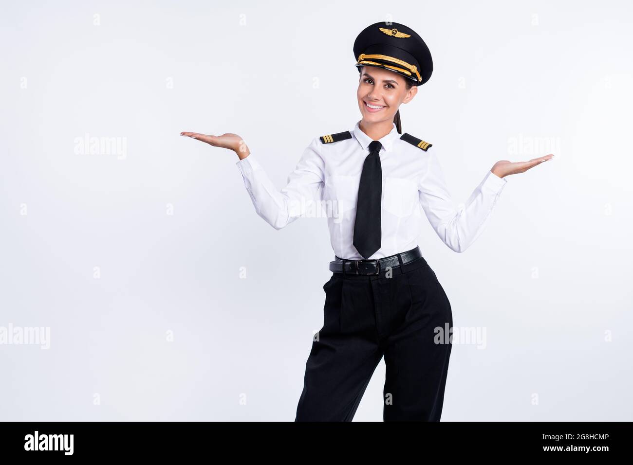 Ritratto di bella ragazza allegra pilota che tiene sul palmo spazio copia due varianti isolate su sfondo bianco Foto Stock