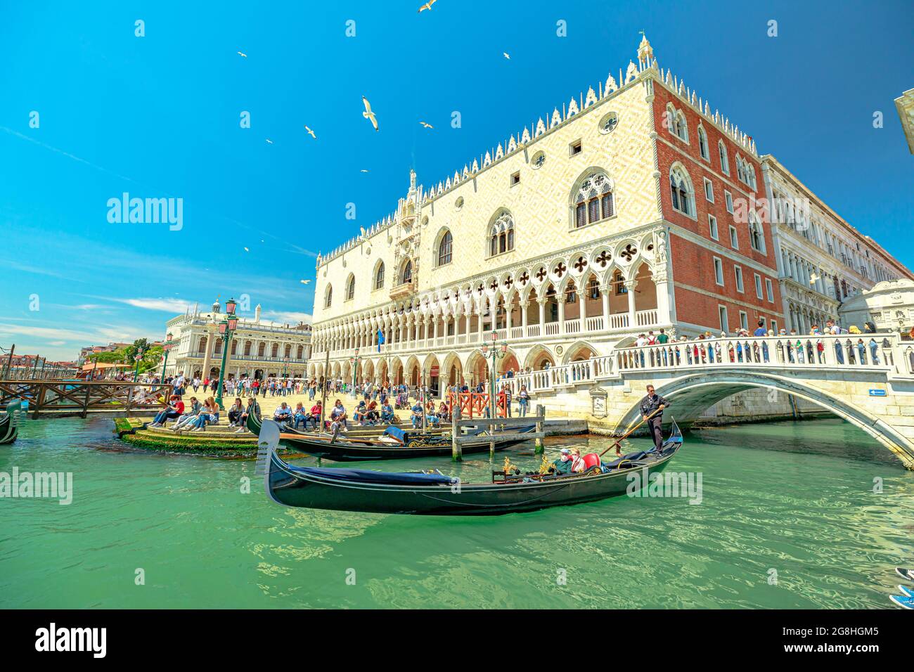 Venezia, Italia - 9 maggio 2021: Gondole tradizionali per la crociera turistica sul canale della Giudecca in Piazza San Marco con il Palazzo Ducale. Il principale e più grande Foto Stock