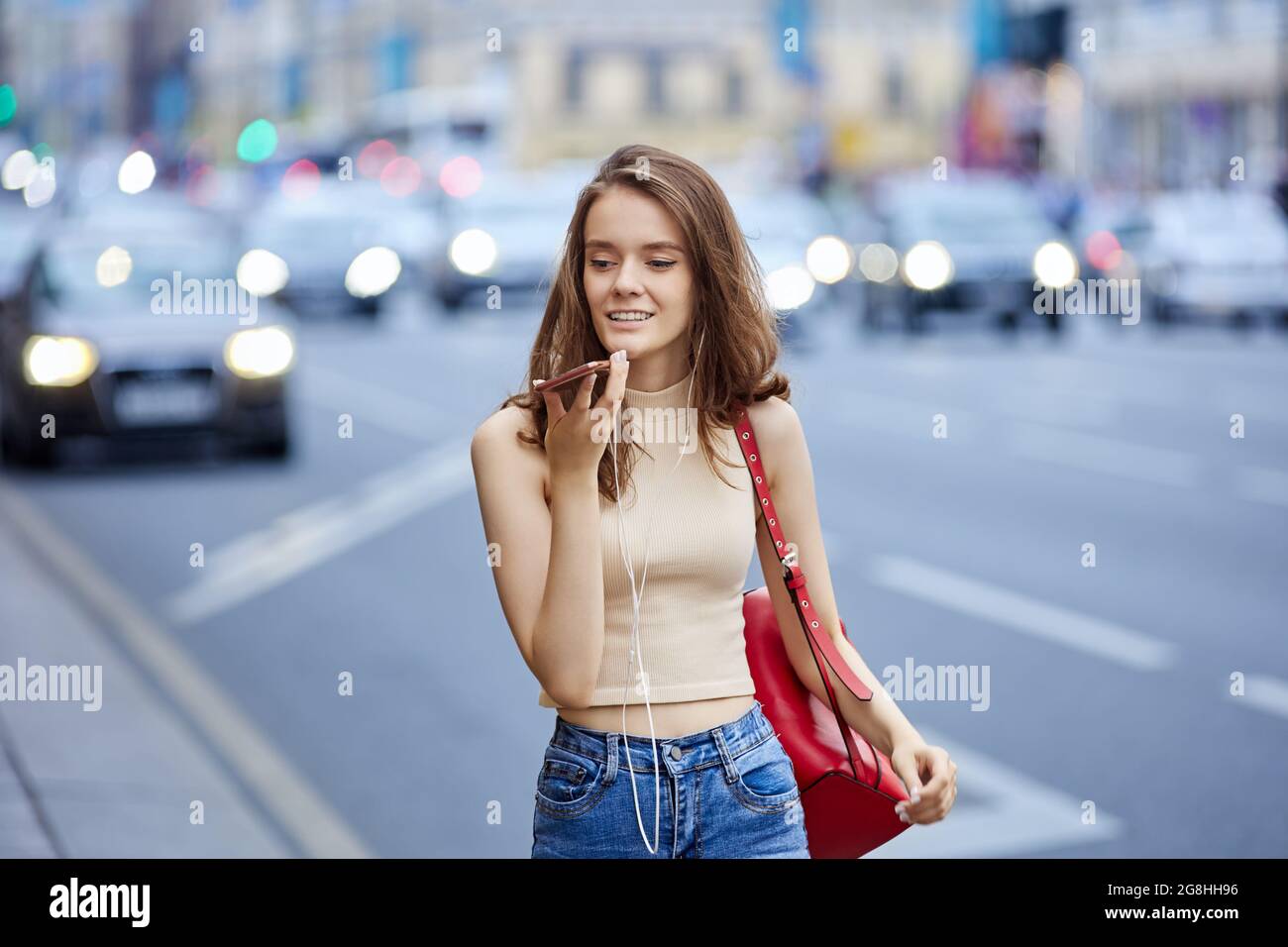 Bella giovane donna sta usando lo smartphone per parlare in linea all'aperto. Foto Stock
