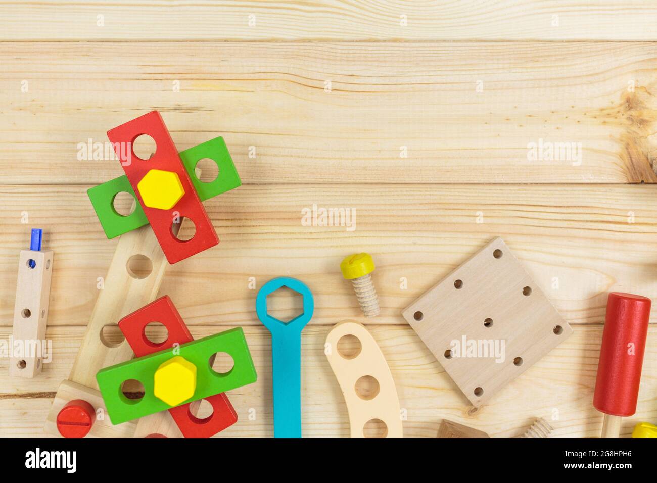 Un colorato kit da costruzione in legno per bambini su legno. Set di attrezzi su tavolo di legno. Giochi e strumenti per i bambini in età prescolare o in asilo. Naturale, eco-patatine Foto Stock
