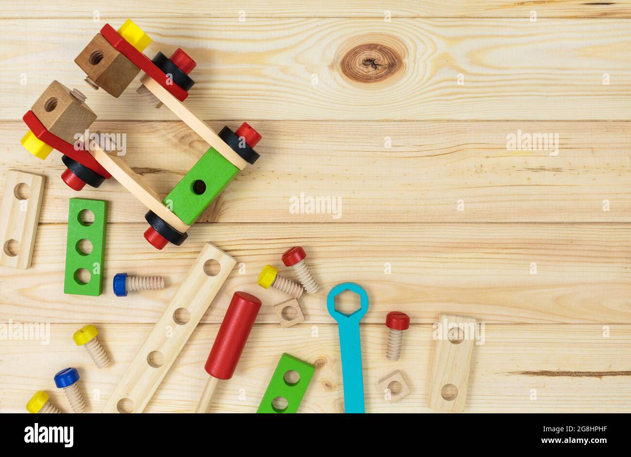 Un colorato kit da costruzione in legno per bambini su legno. Set di attrezzi su tavolo di legno. Giochi e strumenti per i bambini in età prescolare o in asilo. Naturale, eco-patatine Foto Stock