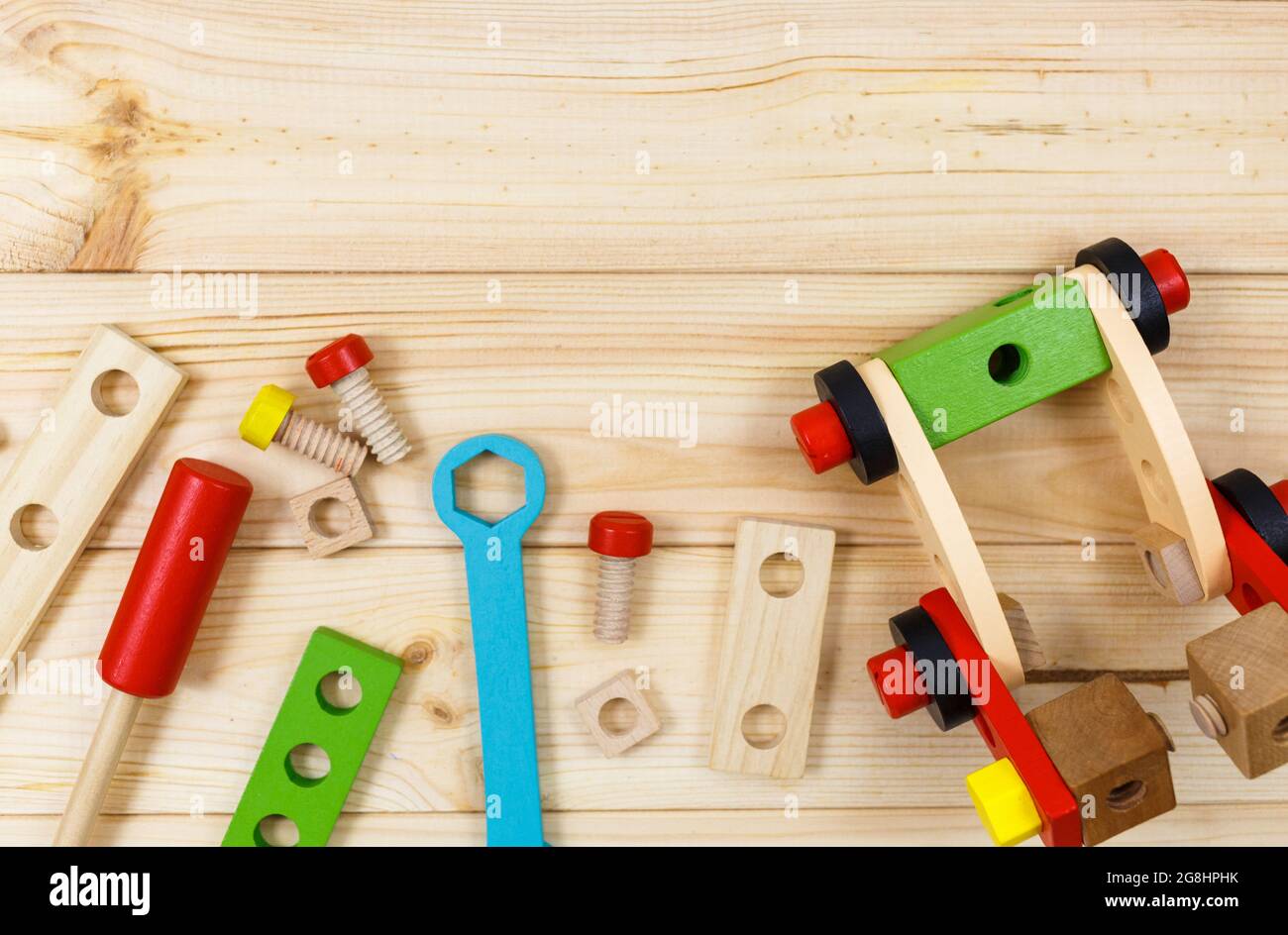 Un colorato kit da costruzione in legno per bambini su legno. Set di attrezzi su tavolo di legno. Giochi e strumenti per i bambini in età prescolare o in asilo. Naturale, eco-patatine Foto Stock
