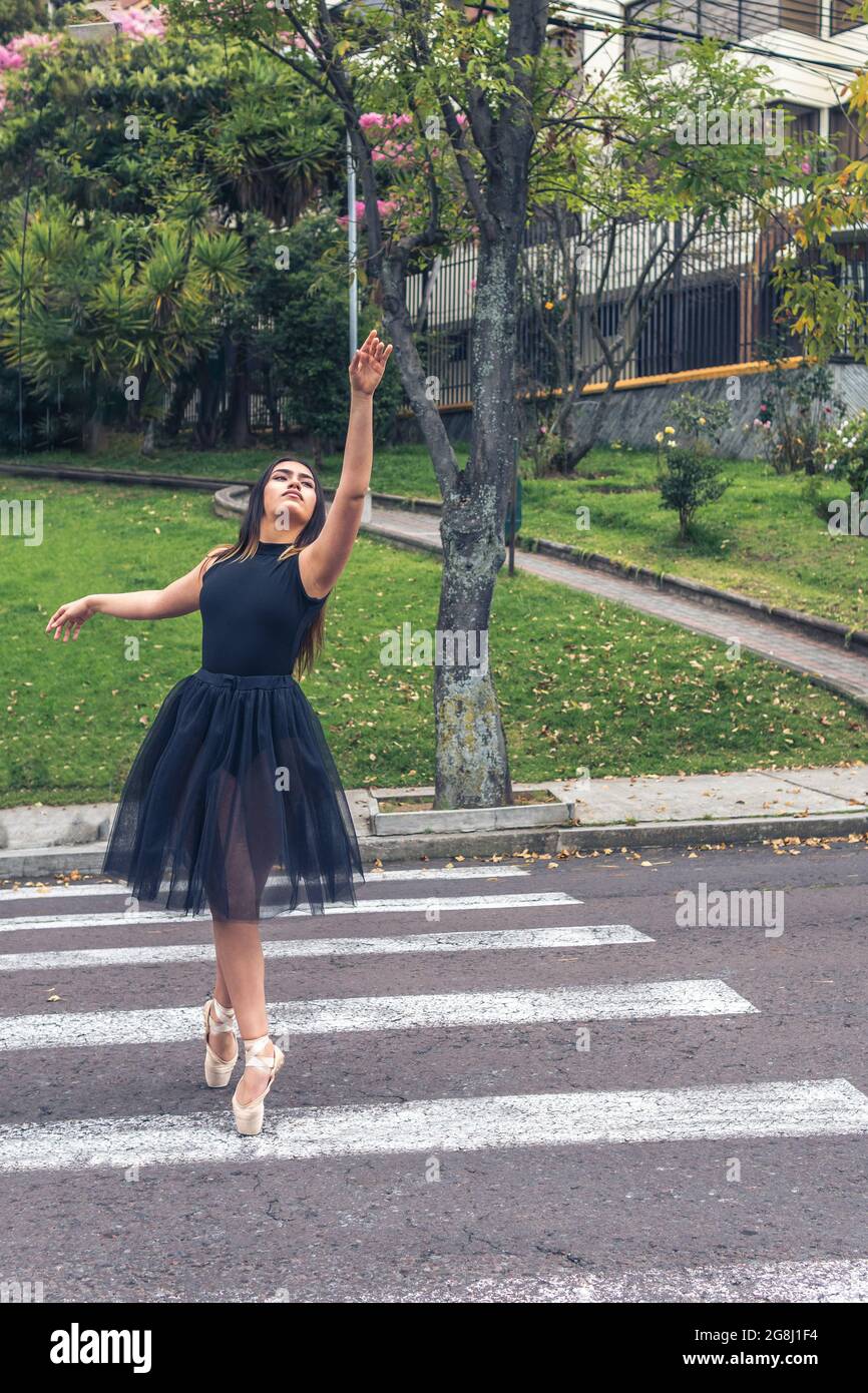 Ballerina in tuta nera e scarpe da ballo che ballano in strada in una  traversata pedonale con un braccio in su Foto stock - Alamy