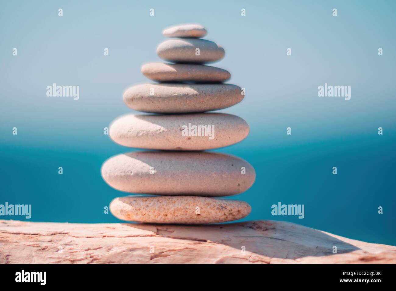 Equilibrata piramide di ciottoli sulla spiaggia in una giornata di sole. Abstract Sea bokeh sullo sfondo. Messa a fuoco selettiva. Pietre Zen sulla spiaggia di mare, meditazione Foto Stock