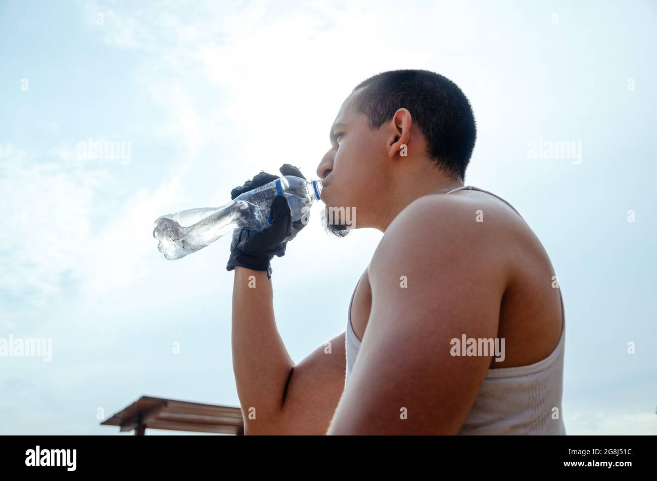 Giovane atleta esausto che beve acqua fresca per rinfrescarsi durante una pista di corsa. Foto Stock
