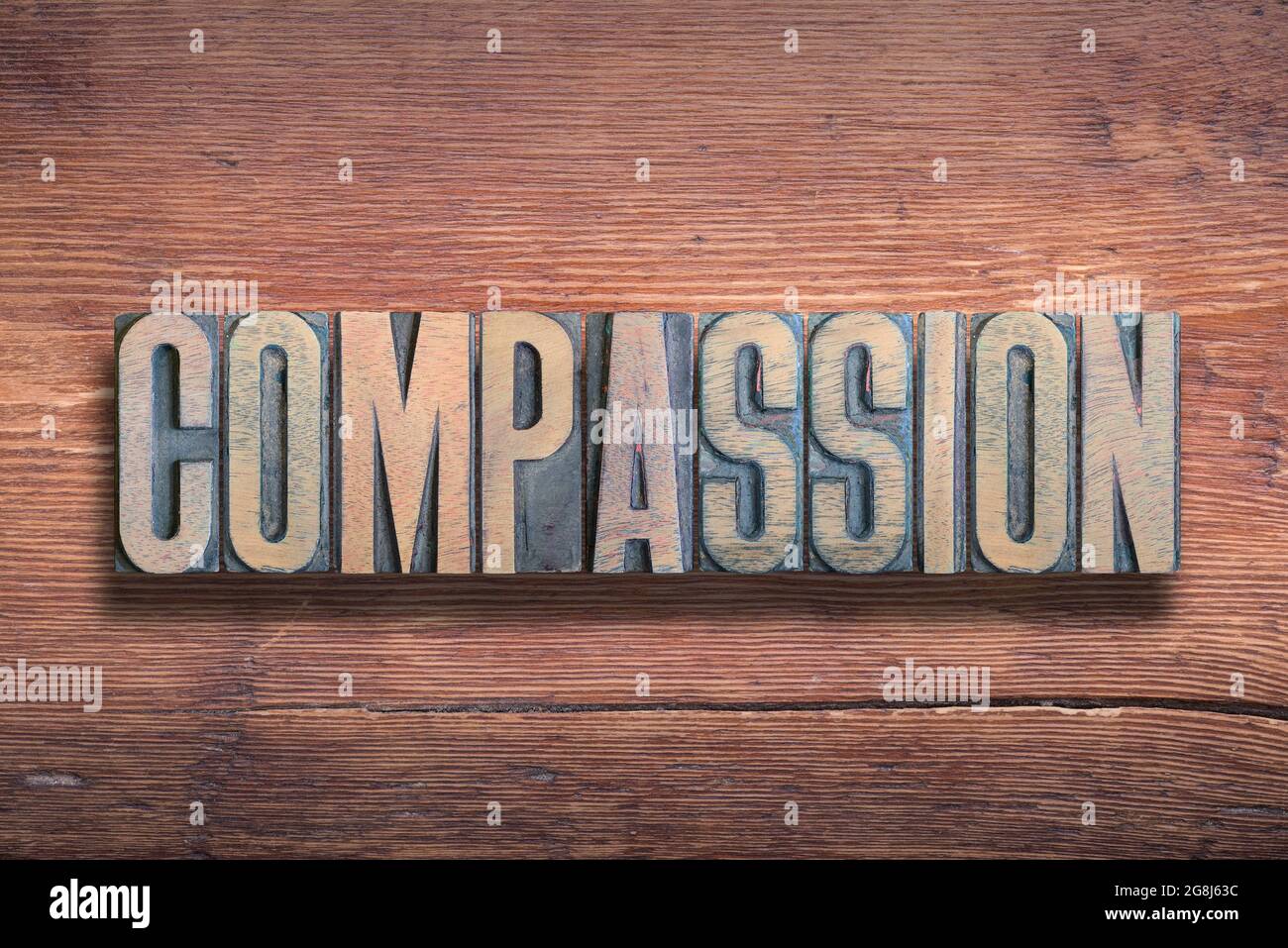parola di compassione combinata su una superficie di legno verniciato d'epoca Foto Stock