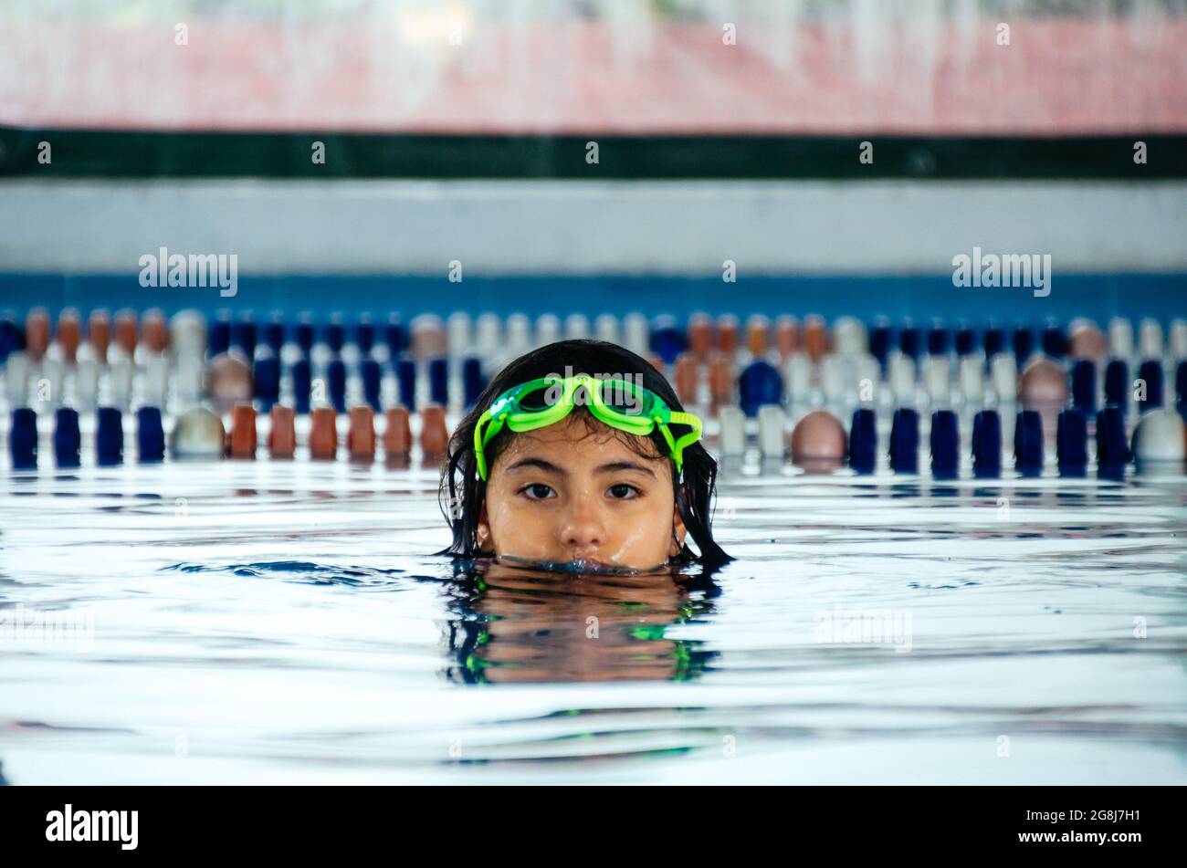 Closeup ritratto di carina piccola ragazza peruviana che nuota in piscina, felice bambino che si diverte in acqua. Foto Stock