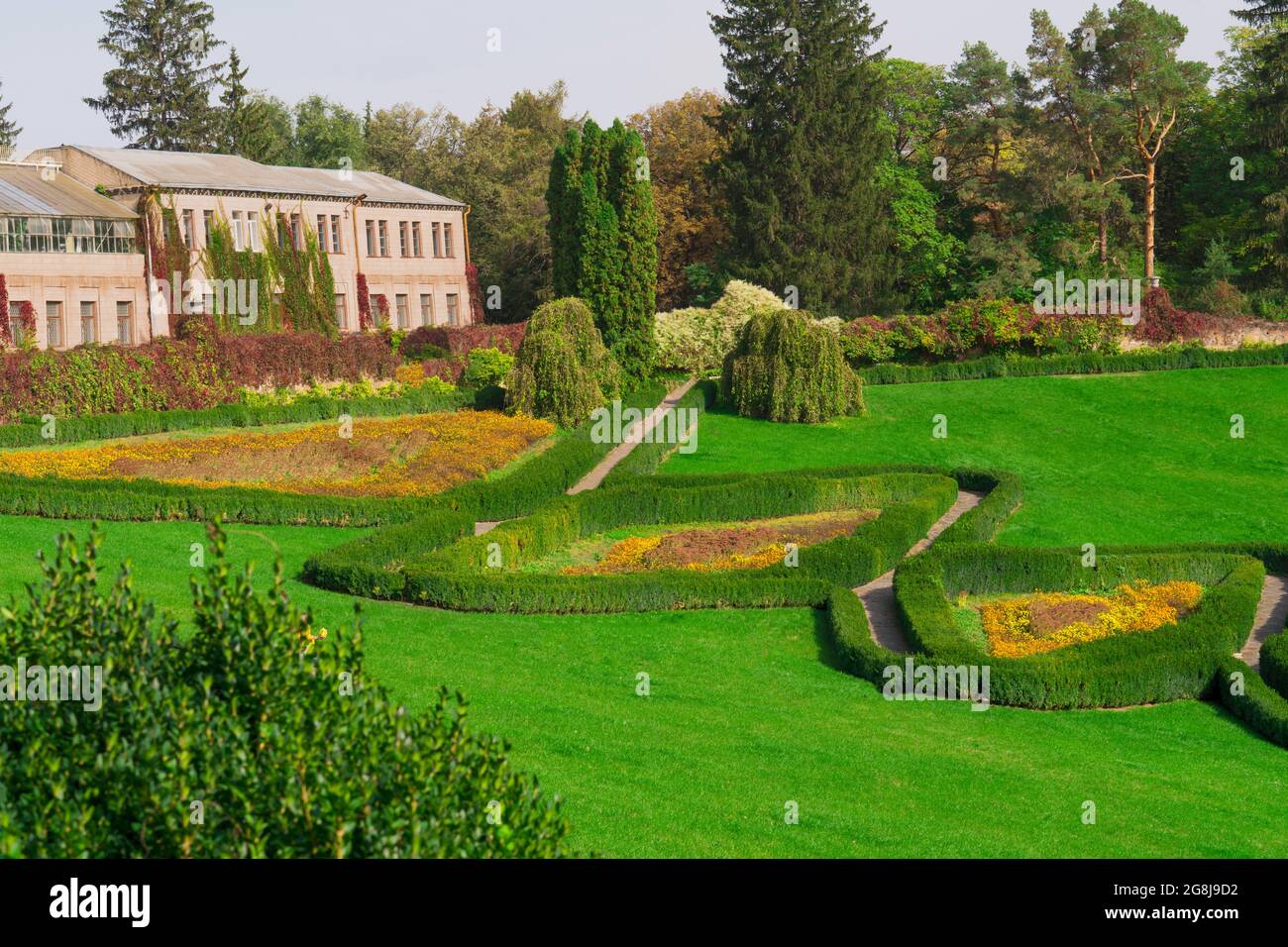 Verde prato curato nel parco, lungo i quali si estendono sentieri, avvolti su entrambi i lati con arbusti e fiori, e si estendono fino alla casa, dietro la quale il Foto Stock