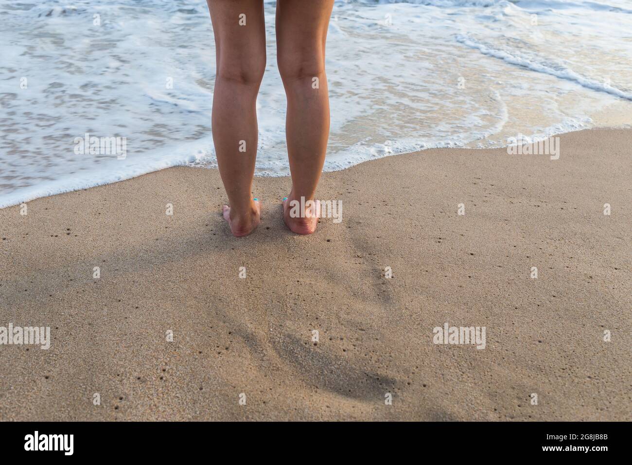 L'onda mi viene in piedi sulla sabbia e attendo alla spiaggia. Vista dall'alto verso il basso Foto Stock