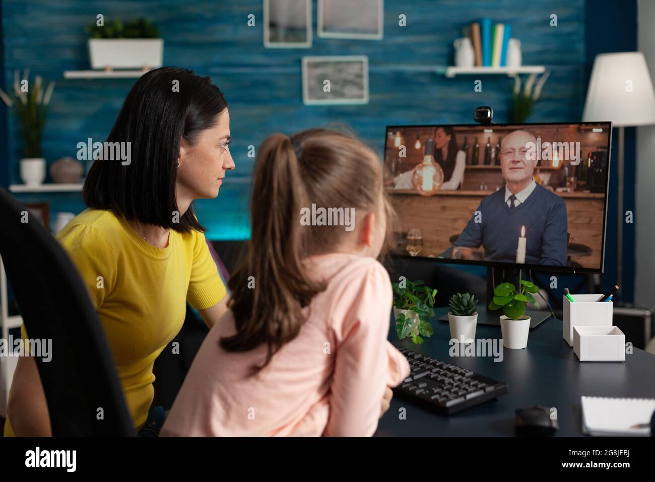 Madre e bimbo che usano Internet per videochiamare una conferenza virtuale online tecnologia moderna. Famiglia di adulti e bambina che parlano con nonno sul sito web app meeting per la comunicazione Foto Stock