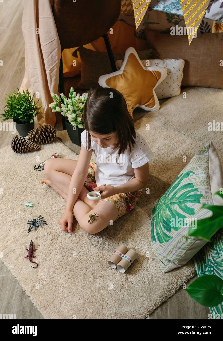 Ragazza che gioca osservando bug giocattolo con una lente di ingrandimento Foto Stock