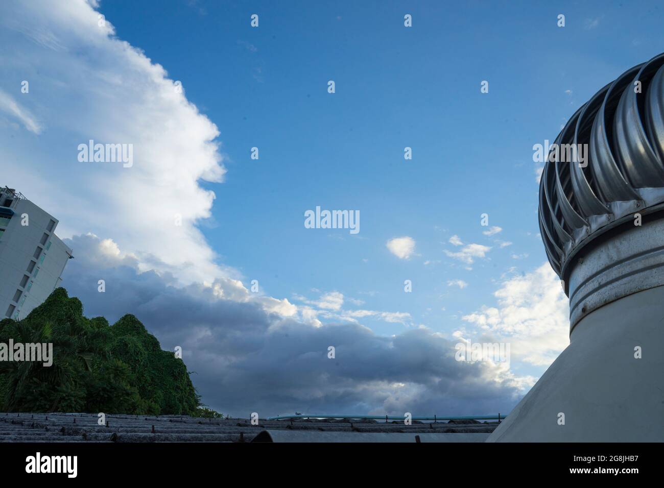 Cloud Blue Sky e Roof Ventilator sul tetto dell'industria per il raffreddamento in modo naturale, affidandosi a venti naturali, messa a fuoco selettiva e tiro a bassa angolazione Foto Stock