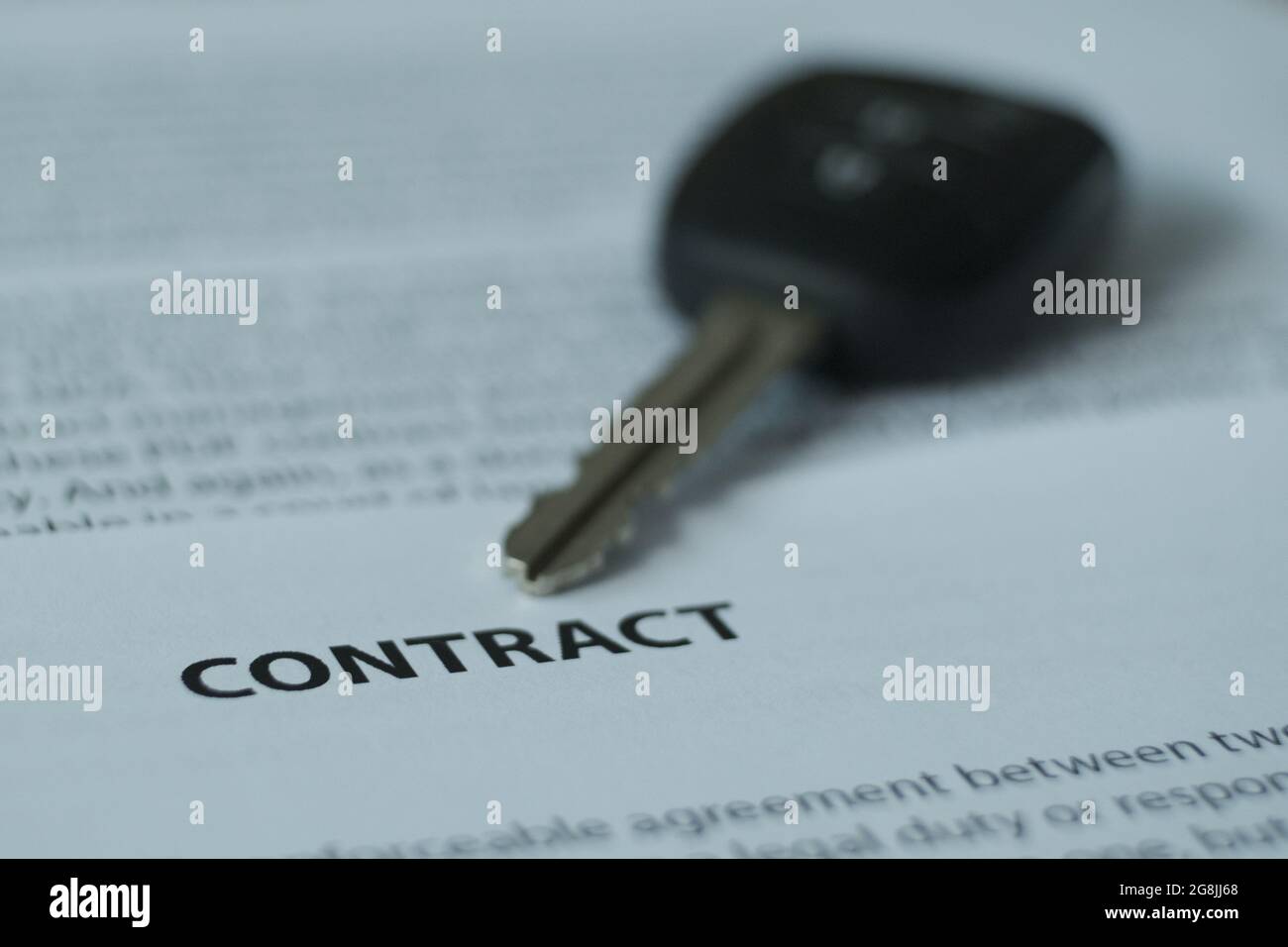 C'è un contratto e le chiavi di automobile sul tavolo, l'enfasi è sul nome del documento e le chiavi. Immagine sfocata. Foto Stock