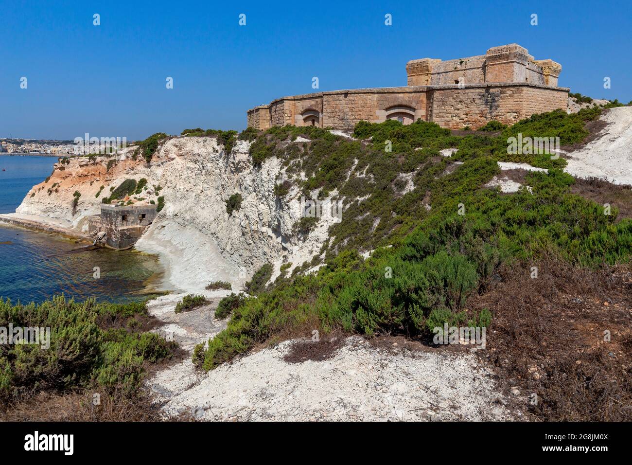 L'antica torre di pietra di San Luciano e il forte sulla baia. Marsaxlokk. Malta. Foto Stock