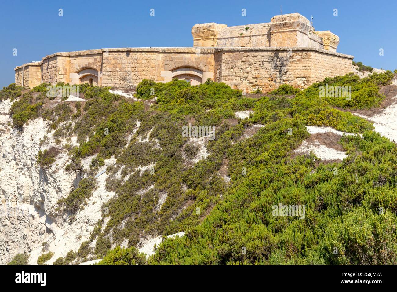 L'antica torre di pietra di San Luciano e il forte sulla baia. Marsaxlokk. Malta. Foto Stock