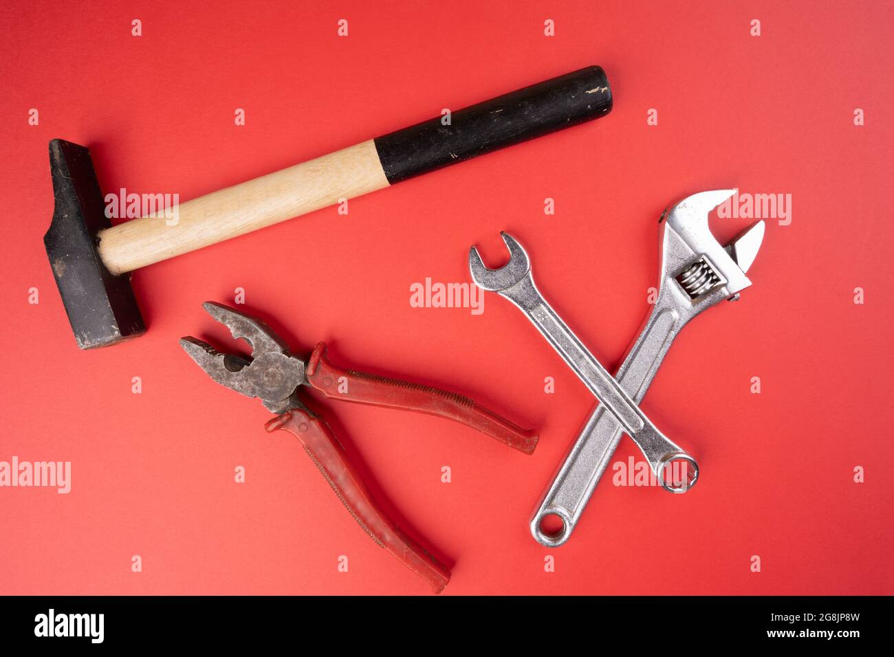 un martello, un paio di pinze e chiavi su una superficie rossa Foto Stock
